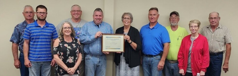 DED Director of Field Operations Sheryl Hiatt (holding plaque at right) recognizes the City of Atkinson for attaining requalification as a Leadership Certified Community.